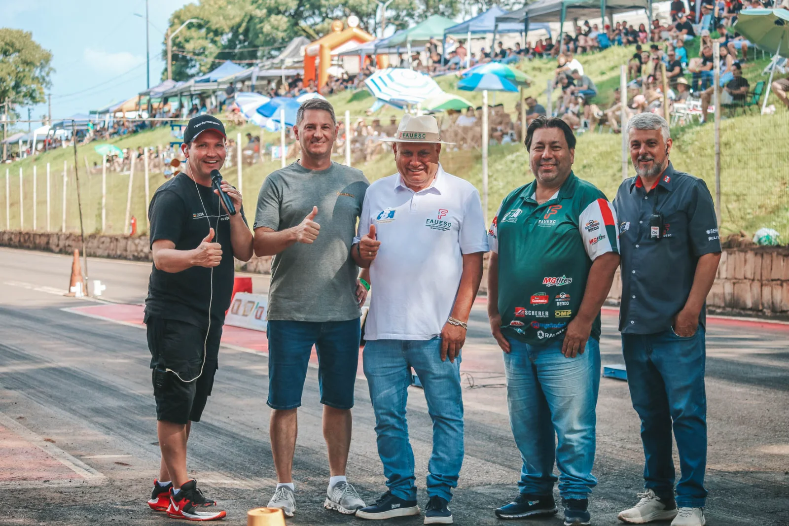 Fabio Chiarello ao lado de dirigentes e organizadores na pista, com a arquibancada cheia ao fundo